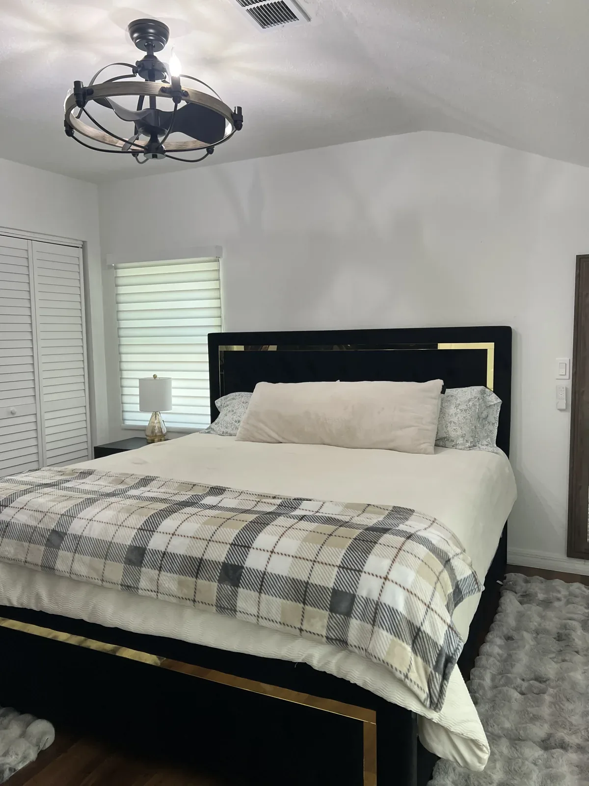 Cleaned bedroom with made bed, plaid bedding and dusted light fitting