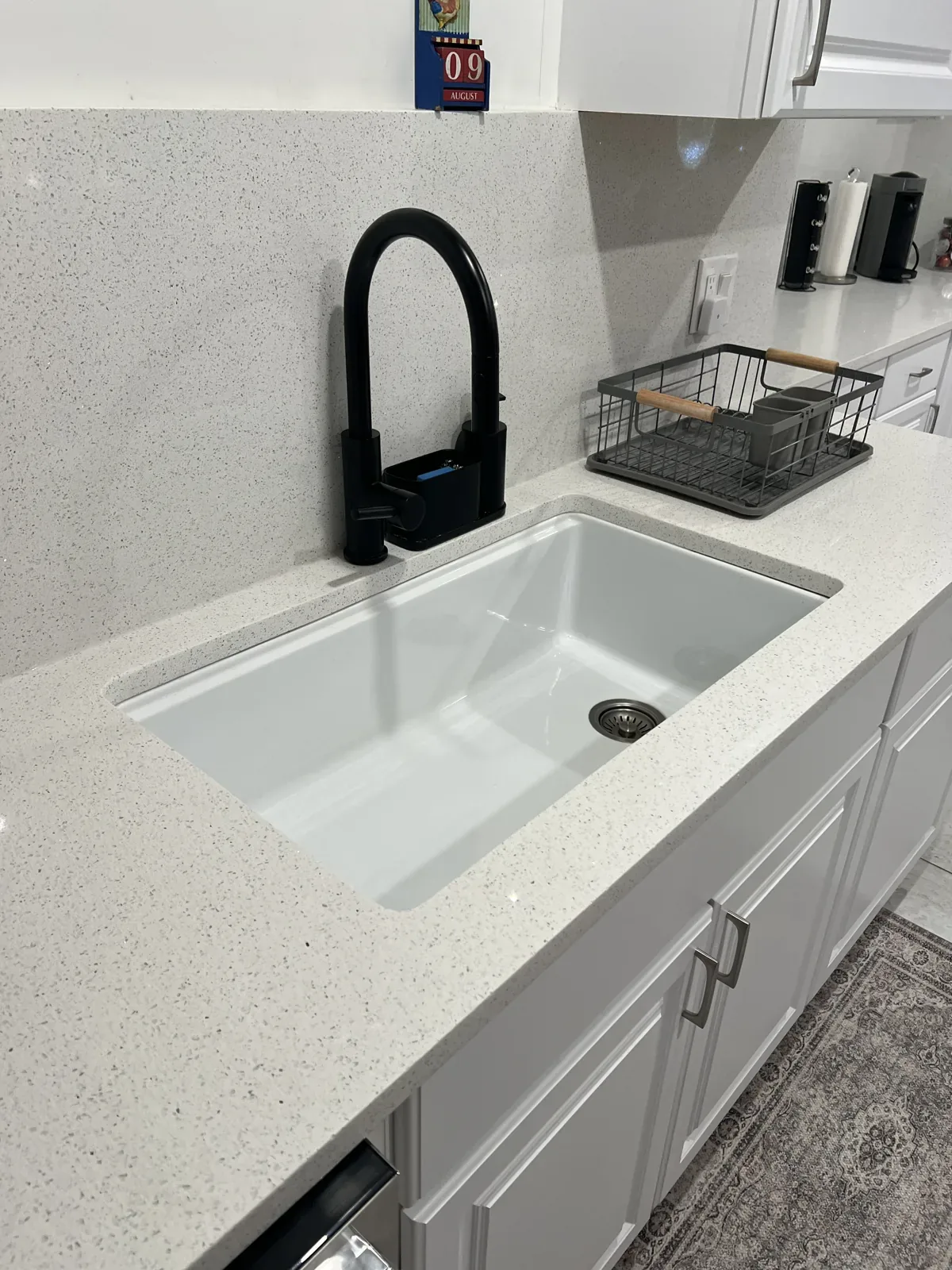 Cleaned kitchen with quartz worktop, matte black tap and polished sink