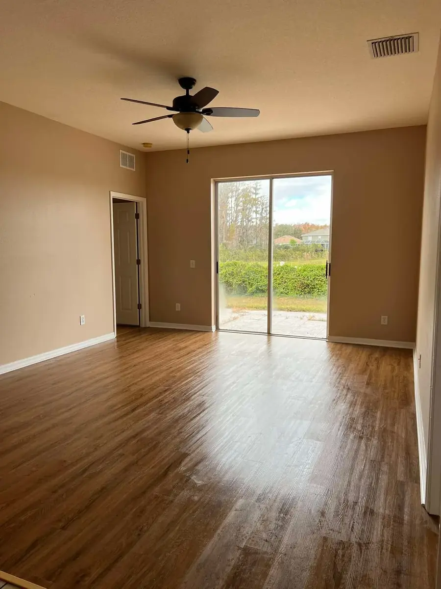 Clean empty bedroom with sliding glass door, hardwood floors