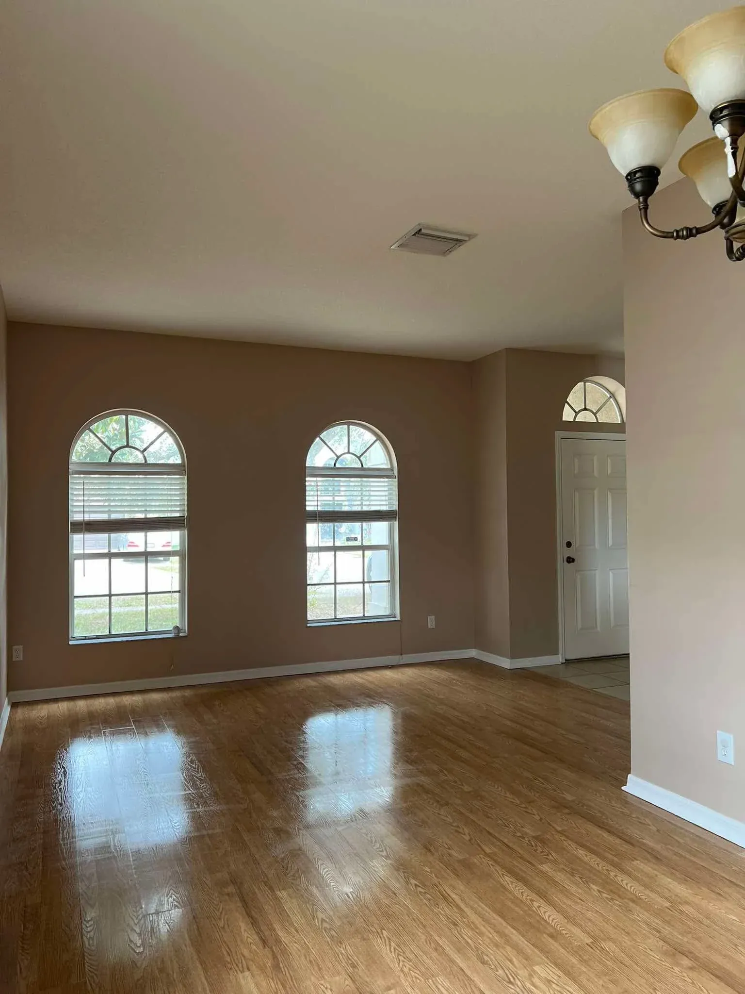 Empty living room after move-out clean, gleaming hardwood floors