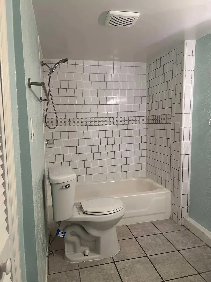 Move-out bathroom from doorway, white tile shower and clean floors